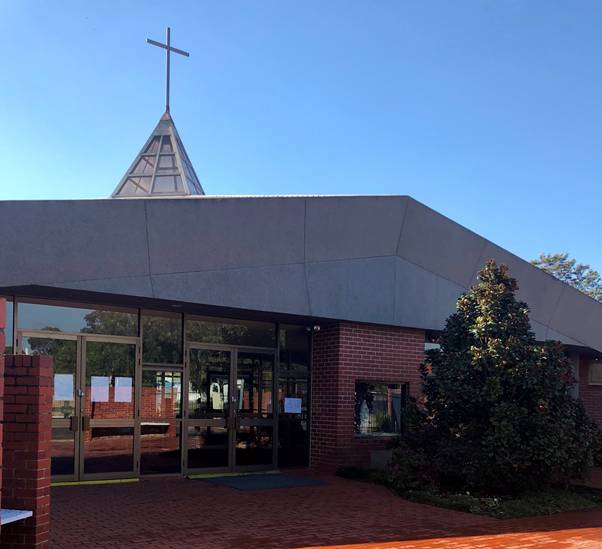 A building with a cross on the roof Description automatically generated